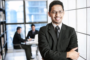 office worker smiling with more office workers working behind them.